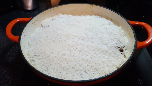 rice added to pan for lamb pulao rice rice added to pan
